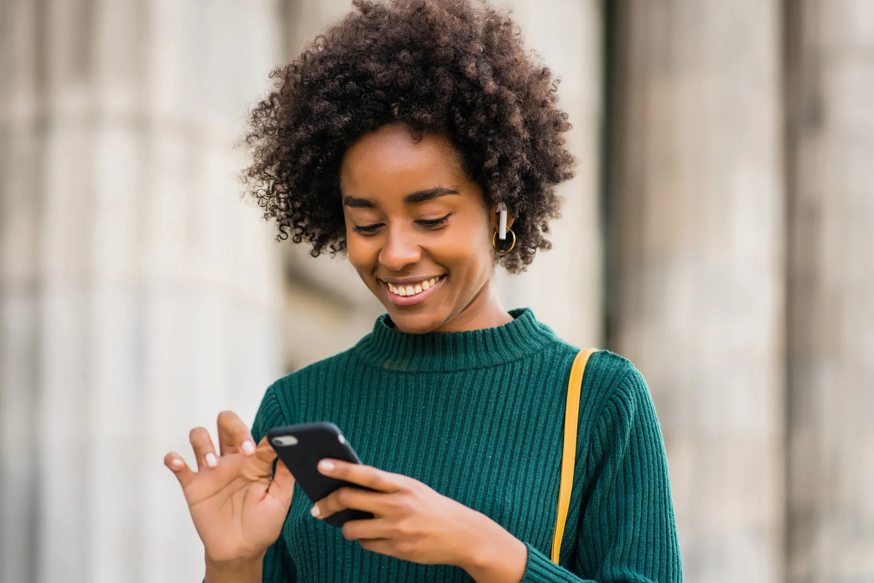 A woman smiles at her phone on the street, mid-booking.
