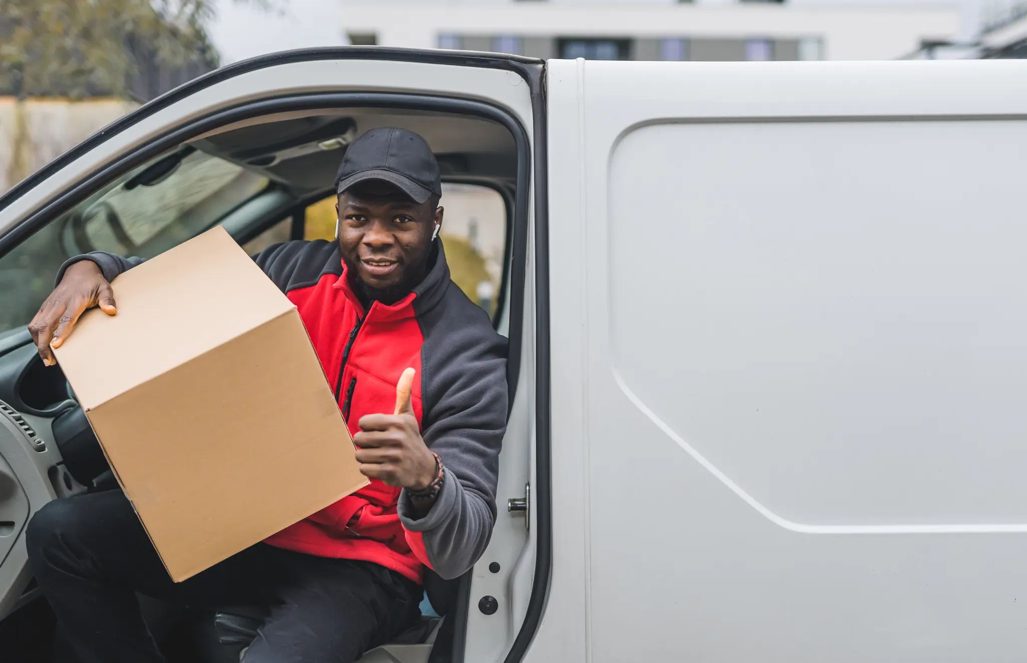 A supplier hands a box down from the door of his van.